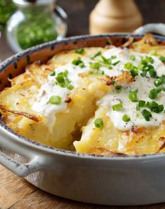 a close up of a casserole dish with cheese and peas in it on a wooden table