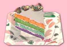 a slice of rainbow cake sitting on top of a paper bag