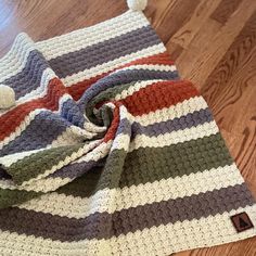 a multicolored crocheted blanket laying on top of a wooden floor