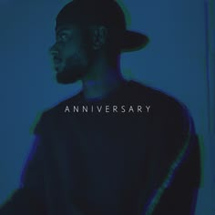 a man wearing a hat and black shirt with the words anniversary on it in white