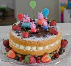 peppa pig cake with strawberries and chocolate frosting on the top, surrounded by other decorations