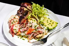 a white plate topped with meat and veggies next to a knife and fork