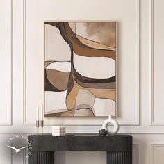 an abstract painting hangs on the wall above a console table with candles and vases