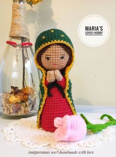 a crocheted doll next to a glass bottle with flowers in it and a small stuffed animal on the table