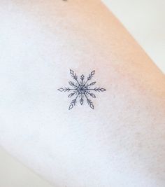 a small snowflake tattoo on the back of a woman's left arm