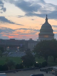 the capital building in washington d c is lit up at dusk with cars parked nearby