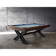 a pool table sitting in front of a wall with concrete walls and cement flooring