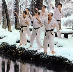 a group of men standing on top of a snow covered ground next to a river