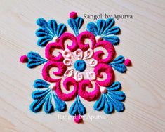 an image of a flower made out of felt on a wooden surface with the words rangoli by apurva written below it