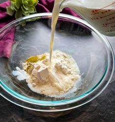 a glass bowl filled with batter being poured on top of the ingredients to make an ice cream treat