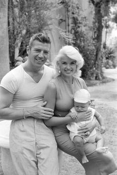 an old black and white photo of two people holding a baby