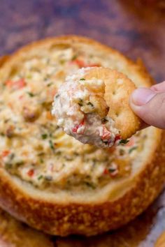 a cracker is being dipped with crab dip