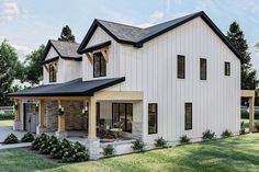 a white house with black roof and windows on the front porch is surrounded by green grass