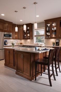 a kitchen with wooden cabinets and an island in the middle, surrounded by bar stools