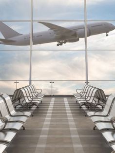 an airplane is flying in the sky over some chairs and benches at an airport terminal