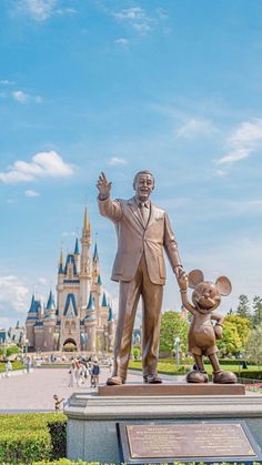 a statue of walt and mickey mouse in front of the castle