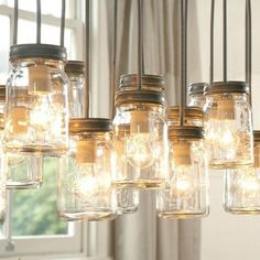 mason jar chandelier with lights hanging from it's sides in front of a window