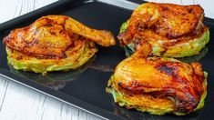 four pieces of cooked chicken sitting on top of a black tray