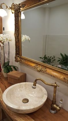 a bathroom with a sink, mirror and flowers on the counter top in front of it