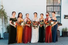 a group of women standing next to each other in front of a building with flowers