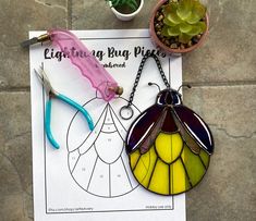 two stained glass bugs are sitting on top of a piece of paper next to some scissors