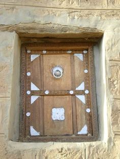 a wooden door with white dots on it and a window in the side of a stone building