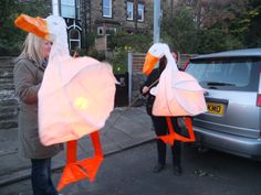 two people are standing on the street with paper swans