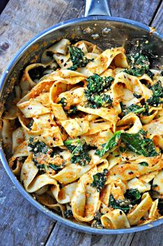 a pan filled with pasta and broccoli on top of a wooden table