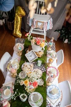 a table set with tea cups, plates and flowers