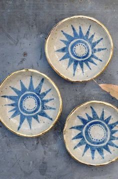 three blue and white bowls sitting on top of a cement floor next to a wooden spoon