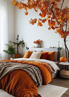 a bed with orange comforters and pillows in a bedroom next to a large tree