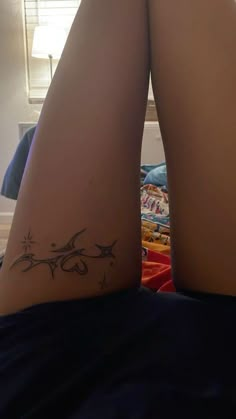 a woman's legs with tattoos on them sitting in front of a bed and looking off into the distance