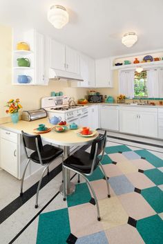 a kitchen with checkered flooring and white cabinets is pictured in this image, there are two black chairs at the table