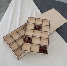 two open boxes sitting on top of a white bed next to eachother filled with small objects