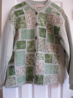 a green and white cardigan hanging on a door with an open jacket over it