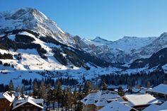 the mountains are covered in snow and surrounded by trees, with buildings on each side