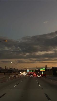 cars are driving down the highway at night with dark clouds in the sky over them