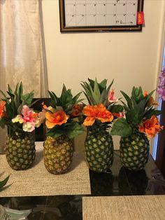 three pineapples with flowers in them sitting on a table