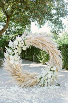 an outdoor wedding ceremony with pamodia and white flowers in the shape of a wreath