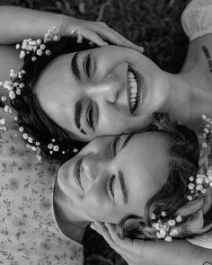 two young women laying on the ground next to each other with flowers in their hair