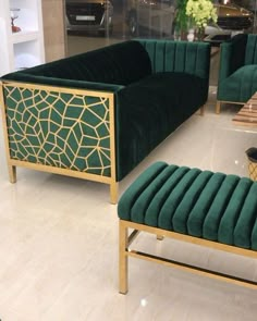 a living room with green velvet couches and matching foot stools