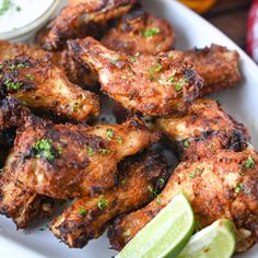 chicken wings with sesame seeds and garnishes next to a bowl of ranch dressing