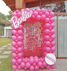 a pink balloon frame with the word barbie written on it in front of a house