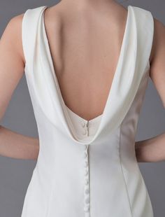 the back of a woman's white dress with buttons and pleated details on it