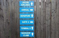 blue directional signs on the side of a wooden fence