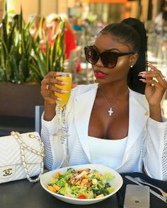 a woman sitting at a table with a plate of food and drink in her hand