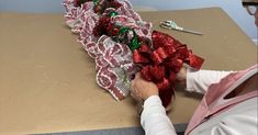 a woman is making christmas bows on a table