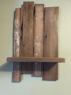 a wooden shelf mounted to the side of a wall with two pieces of wood on it