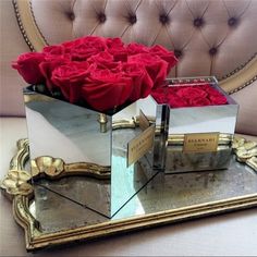 two mirrors with red roses in them sitting on a couch next to a mirror box