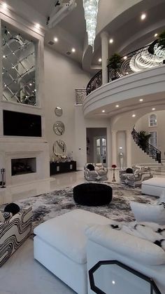 a large living room with white furniture and chandelier hanging from the high ceiling